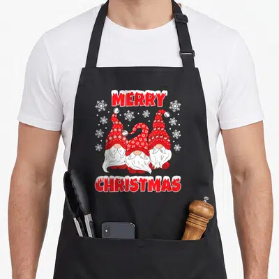 Tablier de cuisine noir avec trois nains de Noël en chapeaux rouges à étoiles et inscription Merry Christmas rouge et blanche.