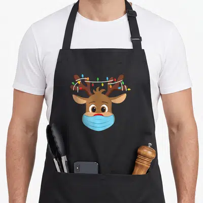 Tablier de cuisine noir avec illustration de Rudolph Renne Nez Rouge portant un masque bleu et des guirlandes lumineuses sur les bois.