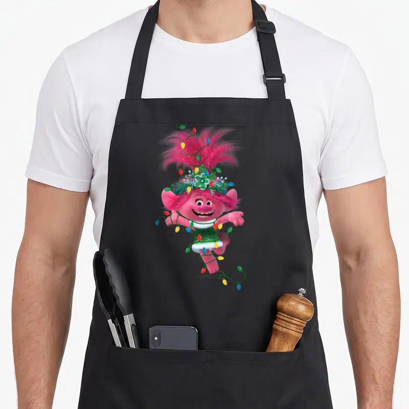 Tablier de cuisine noir avec Poppy des Trolls rose enchaînée à des guirlandes lumineuses multicolores.