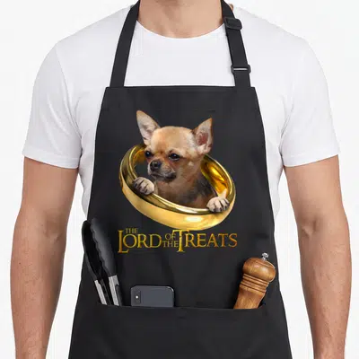 Tablier de cuisine noir avec un chihuahua beige dans une anne dorée et le texte The Lord of the Treats en lettres or.