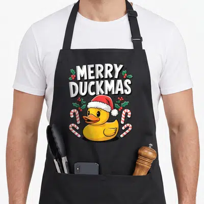 Tablier de cuisine noir avec un canard jaune portant un bonnet de Père Noël et des cannes en sucre.