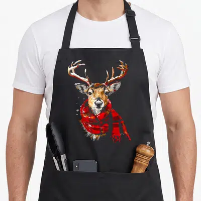 Tablier de cuisine noir avec illustration graphique d'un renne portant une écharpe rouge.