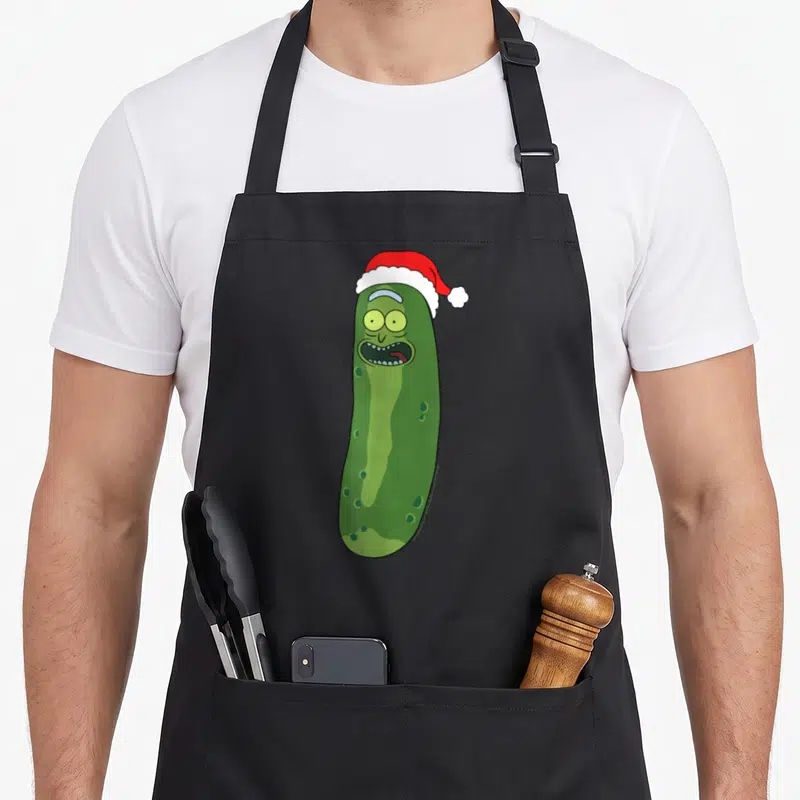 Tablier de cuisine noir avec Pickle Rick portant un bonnet de Père Noël rouge et blanc.
