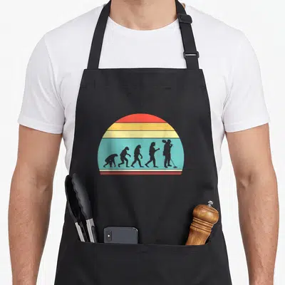 Tablier de cuisine noir avec silhouette évolutive et détecteur de métaux sur fond arc-en-ciel rétro.