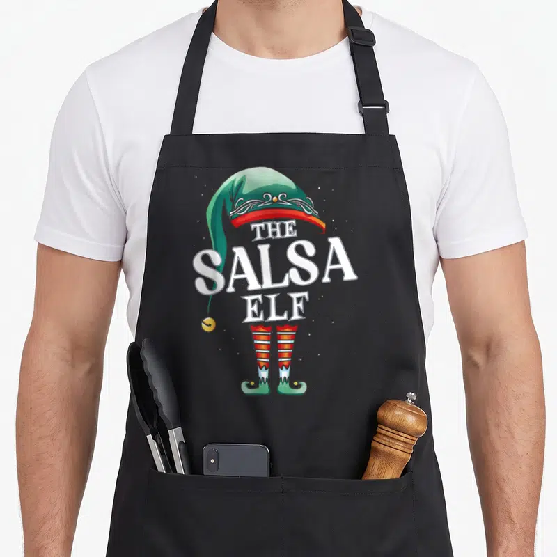 Tablier de cuisine noir avec illustration d'un lutin nommé The Salsa Elf au chapeau vert et bas rayés rouges.