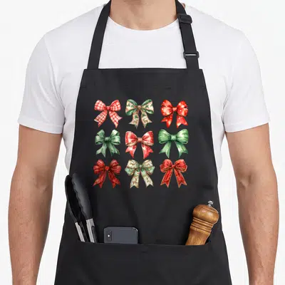 Tablier de cuisine noir avec neuf noeuds de Noël style coquette rouge vert et motifs sapin de Noël imprimés au centre.