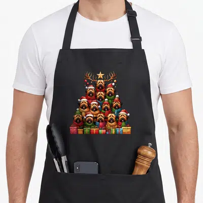 Tablier de cuisine noir avec un sapin de chiens Briards en bonnets et foulards colorés surmonté d'une étoile dorée.