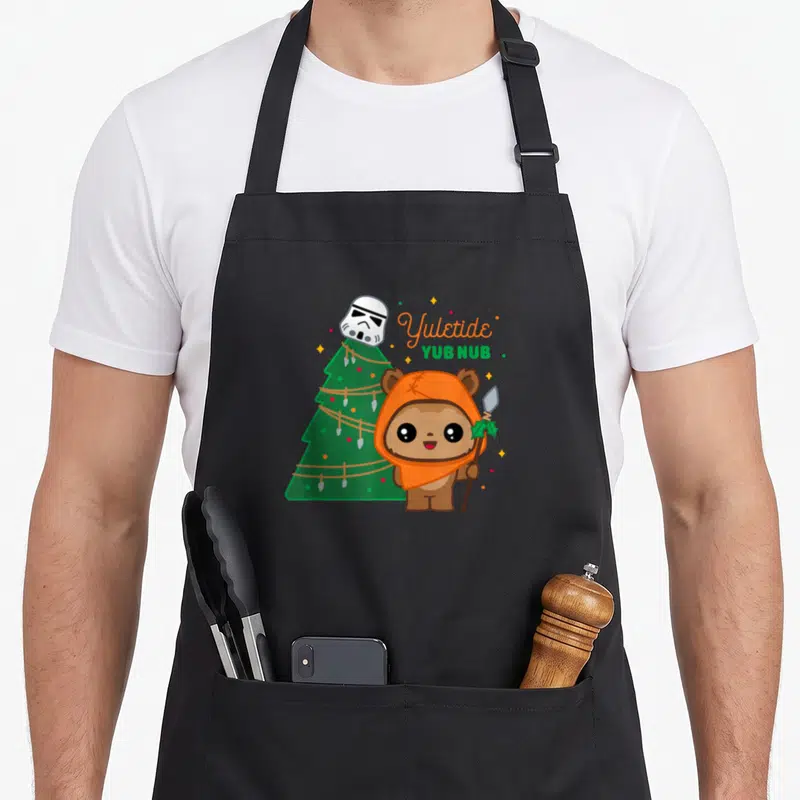 Tablier de cuisine noir avec Wicket Ewok, sapin et texte Yuletide Yub Nub imprimé en couleur.