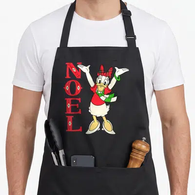 Tablier de cuisine noir avec Daisy Duck en écharpe et le texte NOEL vertical en rouge orné d'étoiles.