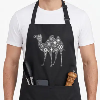 Tablier de cuisine noir avec un chameau stylisé composé de multiples motifs de flocons de neige blancs sur le devant.