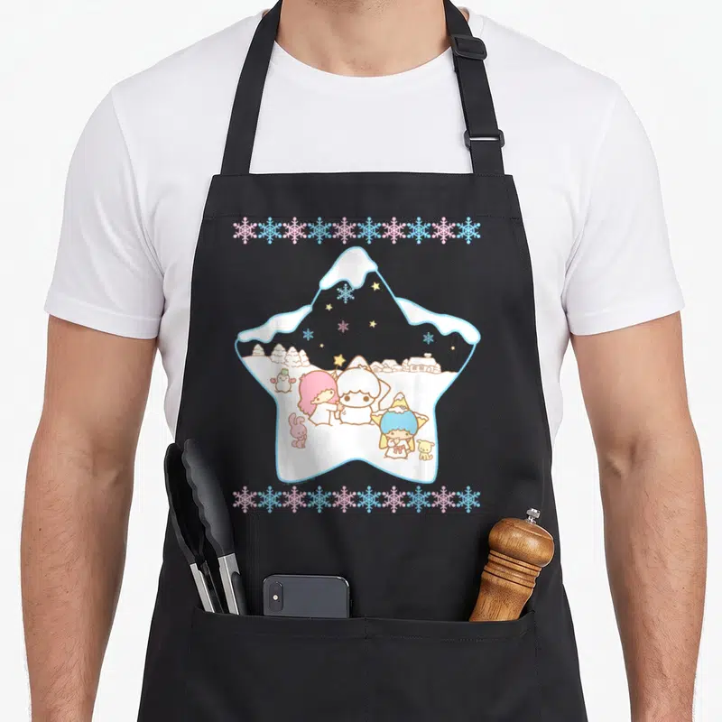 Tablier de cuisine noir avec une illustration en forme d'étoile montrant les Little Twin Stars dans un décor de neige et de flocons colorés.