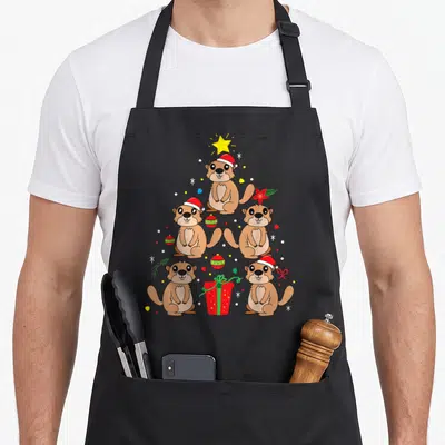 Tablier de cuisine noir avec une illustration d'arbres de Noël composés de marmottes et de décorations festives colorées.