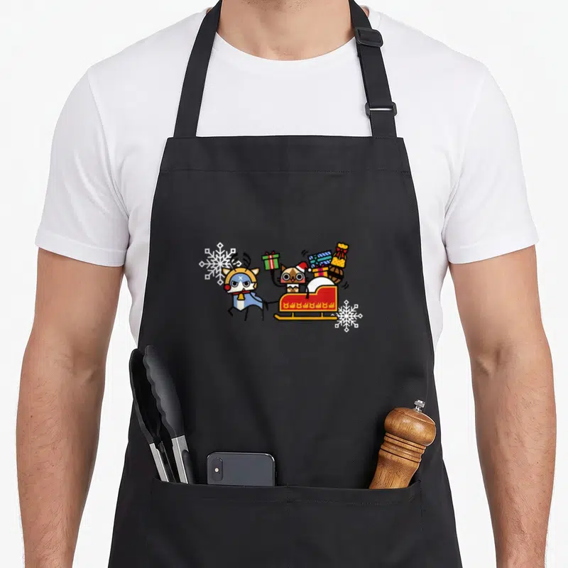 Tablier de cuisine noir avec un Palamute en renne tirant une traînée de cadeaux colorés.
