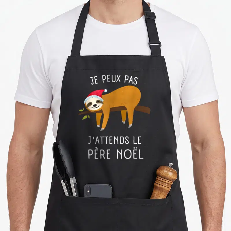 Tablier de cuisine noir avec un paresseux en bonnet de Père Noël et texte blanc Je peux pas j'attends le Père Noël.