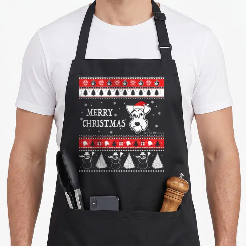 Tablier de cuisine noir avec illustration de Schnauzer en bonnet de Noël et motifs festifs rouges et blancs.
