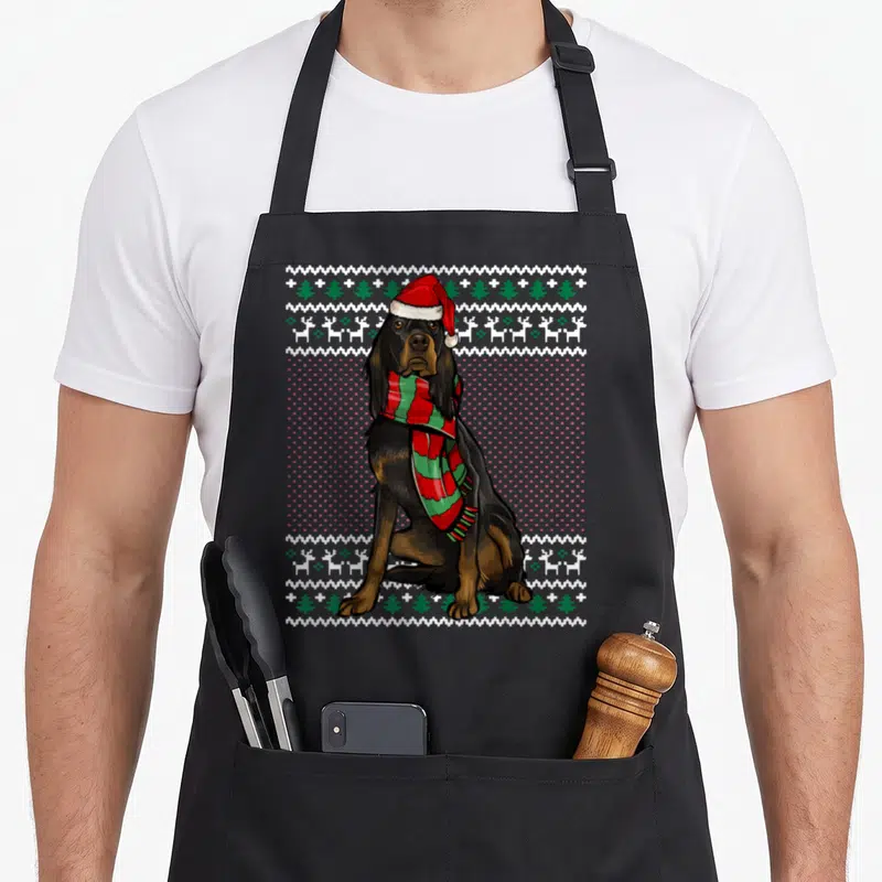 Tablier de cuisine noir avec illustration d'un setter Gordon Noel portant un bonnet de Père Noël et une écharpe festive.