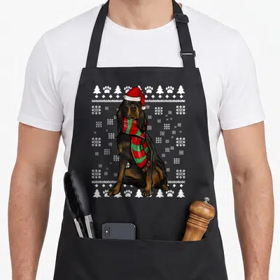 Tablier de cuisine noir avec illustration d'un chien Gordon portant un bonnet de Père Noël et une écharpe à carreaux.