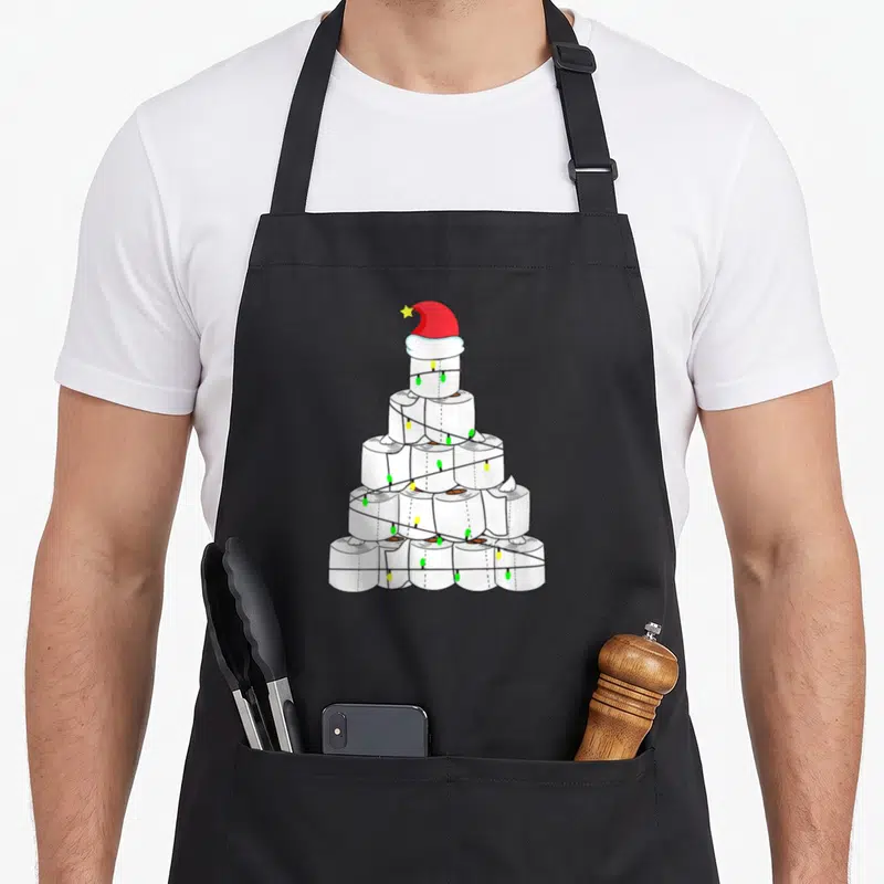 Tablier de cuisine noir avec illustration d'un arbre de Noël constitué de rouleaux de papier hygiénique ornés d'une guirlande et d'un bonnet rouge.