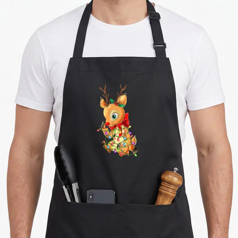 Tablier de cuisine noir avec un renne mignon enfilé dans un éclairage de cadeaux colorés.