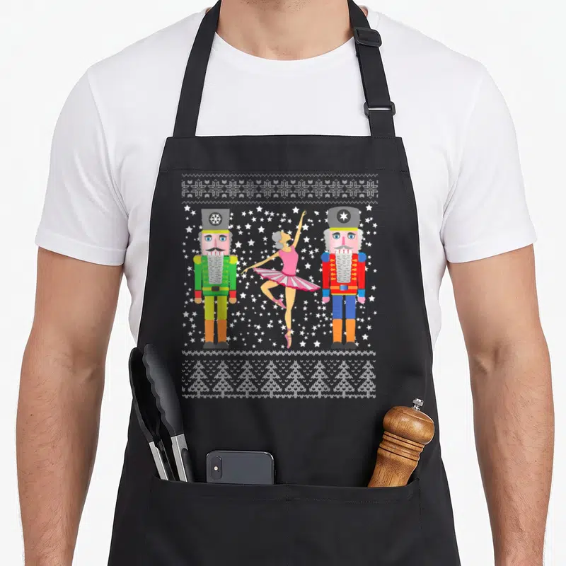 Tablier de cuisine noir avec illustration de deux Casse-Noisettes et une ballerine sur fond d'étoiles blanches.