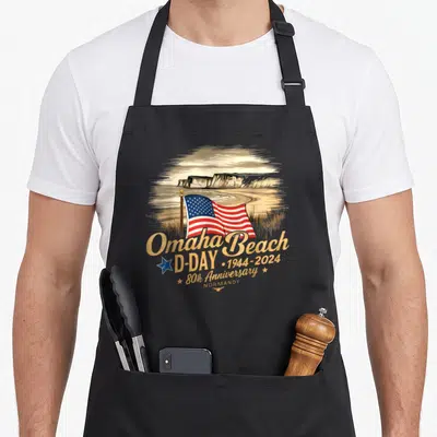 Tablier de cuisine noir avec illustration du drapeau américain sur les falaises d'Omaha Beach en style vintage.