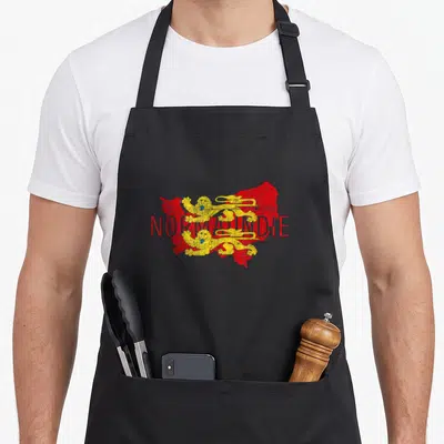 Tablier de cuisine noir avec carte rouge de Normandie et deux lions dorés superposés au texte NORMANDIE en rouge.