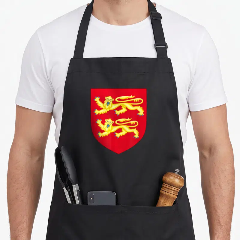 Tablier de cuisine noir avec les armoiries de Normandie montrant trois lions d'or sur un écu rouge vif.