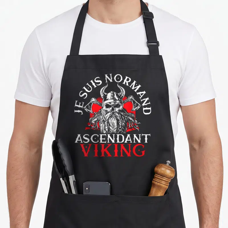 Tablier de cuisine noir avec illustration d'un viking barbu coiffé de cornes et les textes Je Suis Normand Ascendant Viking imprimés en blanc et rouge.
