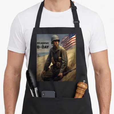Tablier de cuisine noir avec illustration d'un soldat sur une plage et un drapeau américain en arrière-plan.