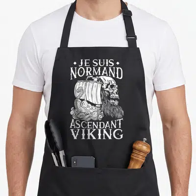 Tablier de cuisine noir avec illustration d'un crâne viking et d'un navire à voile blanc sur fond uni.