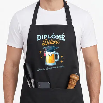 Tablier de cuisine noir avec illustration d'un verre de bière portant une toque de diplômé et du texte humoristique.