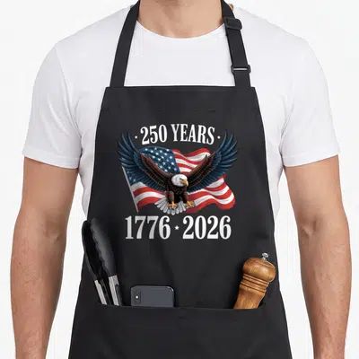 Tablier de cuisine noir avec un aigle aux ailes déployées devant un drapeau américain et l'inscription 250 Years 1776 2026.