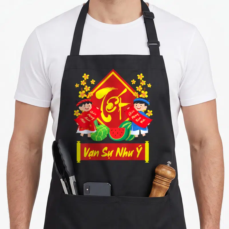 Tablier de cuisine noir avec deux enfants vietnamiens tenant des banderoles rouges devant un grand caractère doré sur fond rouge.