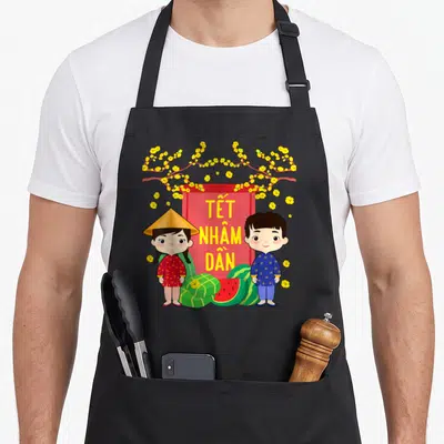 Tablier de cuisine noir avec deux enfants en tenues traditionnelles vietnamiennes et des fleurs jaunes sur fond rouge.
