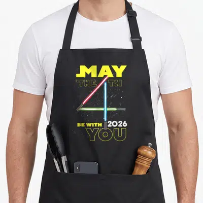 Tablier de cuisine noir avec sabres laser rouge, bleu et vert formant un 4 et texte May The 4th Be With You 2026.
