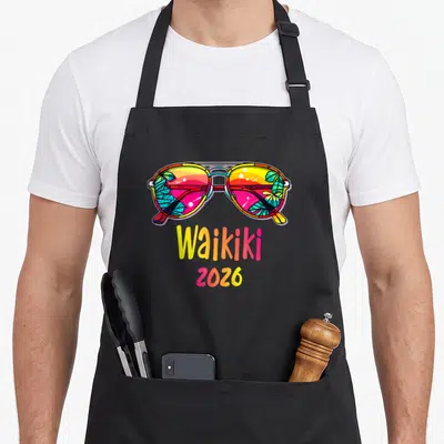 Tablier de cuisine noir avec lunettes de soleil colorées et texte Waikiki 2026 imprimé au centre.