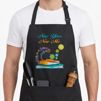 Tablier de cuisine noir avec New Year New Me et livres colorés imprimés sur le devant.