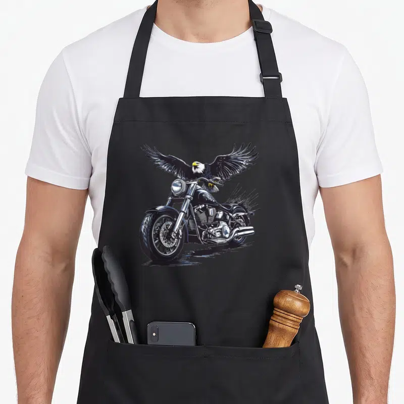 Tablier de cuisine noir avec aigle aux ailes déployées sur une moto noire stylisée.
