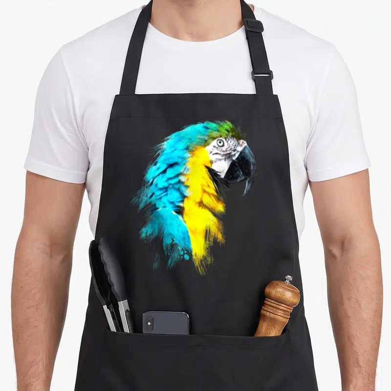 Tablier de cuisine noir avec une illustration aquarelle d'un perroquet aux plumes bleues et jaunes.