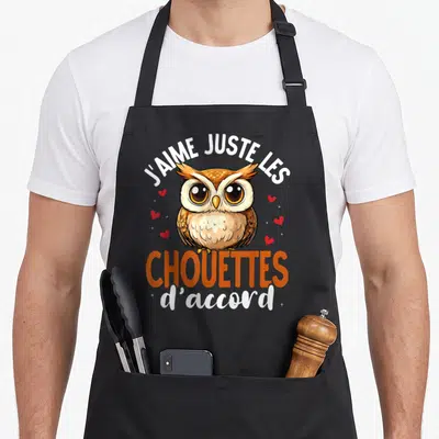 Tablier de cuisine noir avec une chouette marron et le texte J'aime Juste Les Chouettes d'accord entouré de petits cœurs rouges.