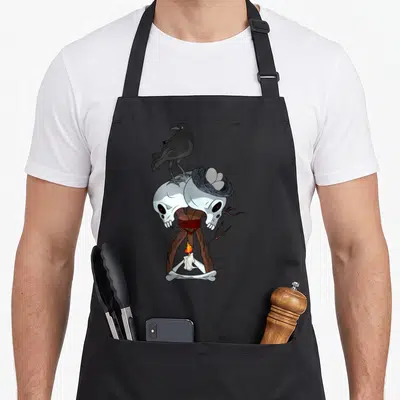 Tablier de cuisine noir avec corbeau, deux crânes, niche d'œufs et petit feu de camp stylisé.