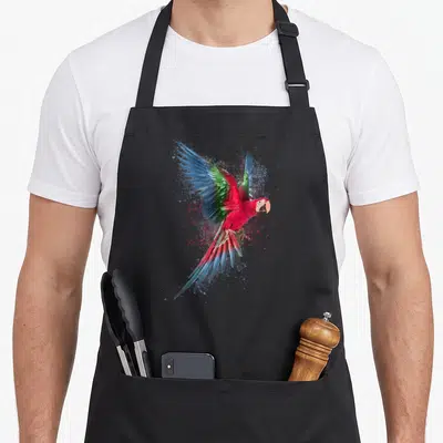 Tablier de cuisine noir avec un perroquet aux ailes déployées et des éclats de couleurs vives.