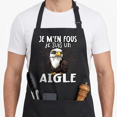 Tablier de cuisine noir avec illustration d'un aigle aux yeux ronds et la phrase Je m'en fous je suis un aigle en lettres blanches.