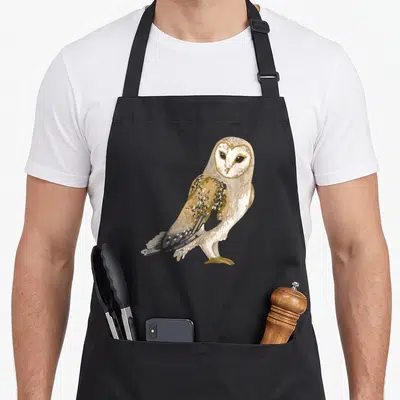Tablier de cuisine noir avec une illustration colorée d'un hibou aux plumes dorées et noires.