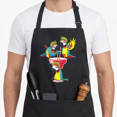 Tablier de cuisine noir avec trois perroquets hawaïens décorés buvant dans un grand verre rose à pailles rouges et blanches.