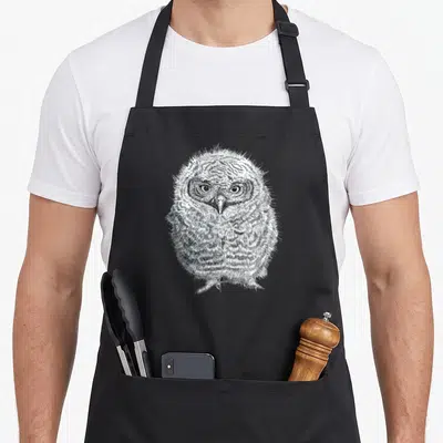 Tablier de cuisine noir avec illustration détaillée d'un jeune hibou Screech aux yeux ronds et plumage texturé.