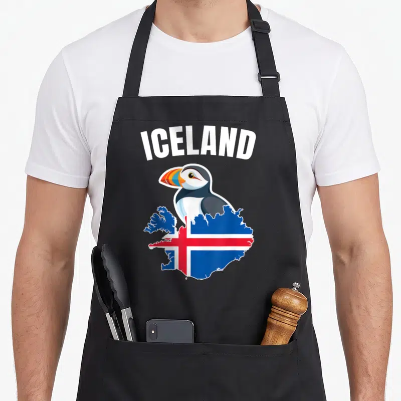 Tablier de cuisine noir avec un macareux coloré posé sur une carte d'Islande aux couleurs du drapeau national sous le mot Iceland.