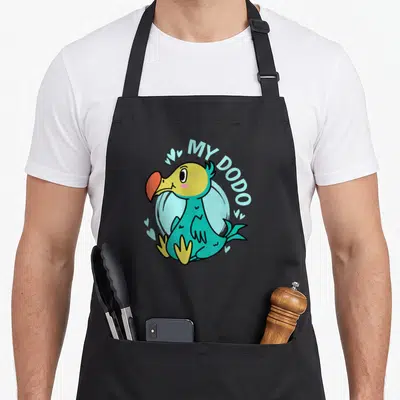 Tablier de cuisine noir avec un dodo cartoon turquoise, bec orange et texte MY DODO entouré de petits cœurs bleus.