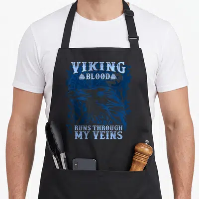 Tablier de cuisine noir avec illustration d'un corbeau bleu et texte viking en anglais.