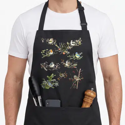 Tablier de cuisine noir avec illustrations naturalistes de merle, moineau, mésange et hibou perchés sur des branches florales.